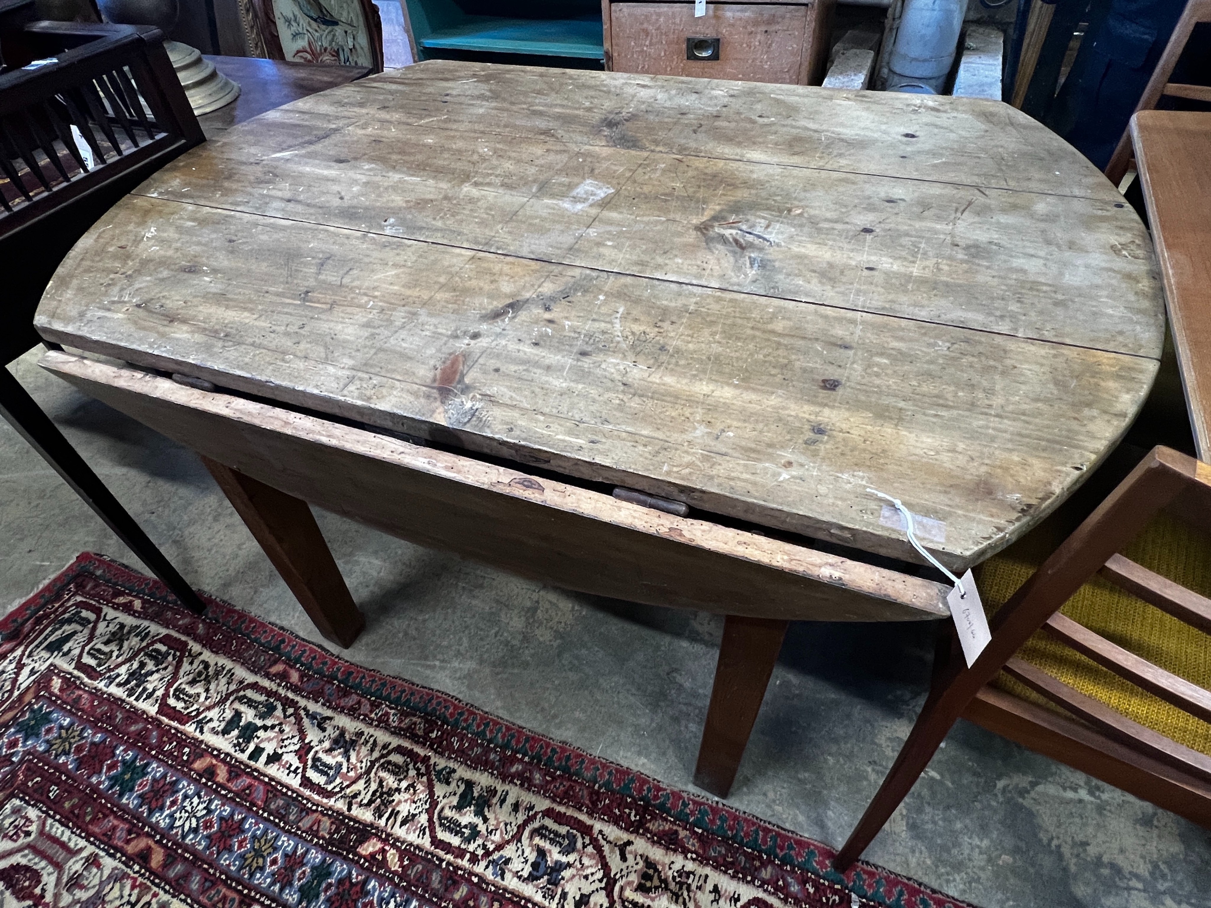 A 19th century French oak and pine circular drop leaf kitchen table, length 130cm, depth 90cm, height 73cm